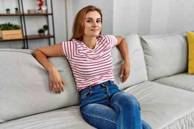 Evdeki koltukta kendinden emin gülümseyen genç bir kadın.