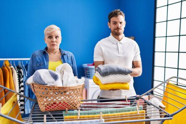 Hispanic mother and son hanging clothes at clothesline skeptic and nervous, frowning upset because of problem. negative person. 