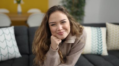 Evdeki kanepede oturan kendine güvenen güzel İspanyol kadın.