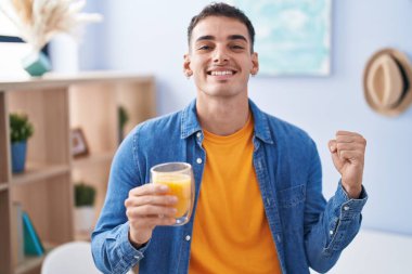 Yakışıklı İspanyol adam bir bardak portakal suyu içiyor gururla bağırıyor, zaferi kutluyor ve başarıyı kollarını kaldırarak kutluyor. 
