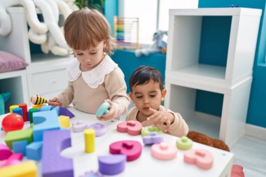 Anaokulunda inşaat bloklarıyla oynayan iki çocuk.