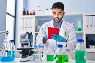 Laboratuvarda dokunmatik ped kullanan genç bir İspanyol bilim adamı üniforması giyiyor.