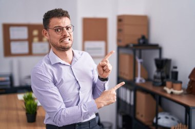 Ofisteki genç İspanyol adam iki eliyle endişeli ve gergin bir ifadeye işaret ediyor. 