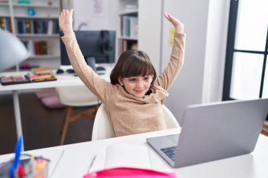 Sevimli İspanyol öğrenci sınıfta kutlama ifadesiyle dizüstü bilgisayar kullanıyor.