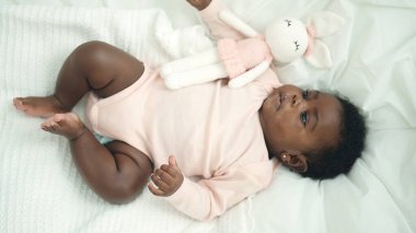 African american baby lying on bed with relaxed expression at bedroom