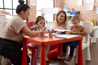 Teachers with boy and girl smiling confident having handcrafts class at kindergarten