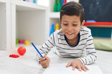 Anaokulunda defterine yazı yazan sevimli İspanyol çocuk.