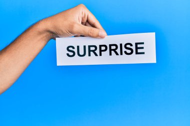 Kafkasyalı bir adamın elinde, mavi arka planda sürpriz sözcüklerle dolu bir kağıt var.