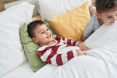 Two kids smiling confident lying on bed at bedroom