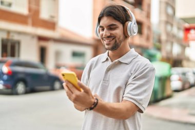 Sokakta müzik dinlerken kendinden emin gülümseyen İspanyol genç adam.