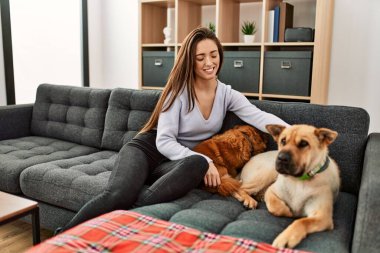 Kanepede oturmuş köpeklerle gülümseyen İspanyol bir kadın.