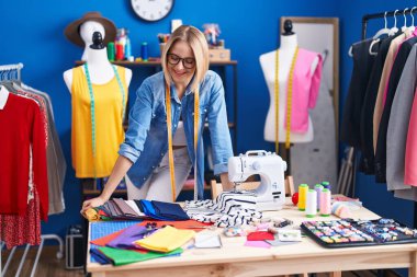 Young blonde woman tailor smiling confident standing at sewing studio