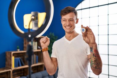 Beyaz adam evinde akıllı telefonla Bitcoin dersi kaydediyor. Gururla bağırıyor, zaferi kutluyor ve kolunu kaldırarak başarıyı kutluyor. 