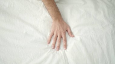 Young hispanic man hand on bed at bedroom