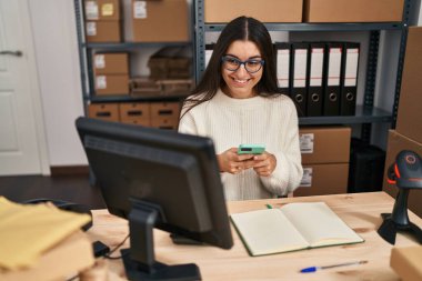 Genç İspanyol kadın ecommerce iş işçisi Ofiste akıllı telefon kullanıyor