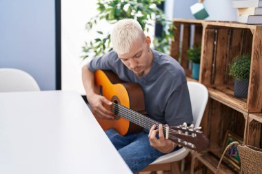 Young caucasian man playing classical guitar at home