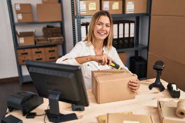 Genç İspanyol kadın ecommerce iş işçisi ofiste boks paketi açıyor