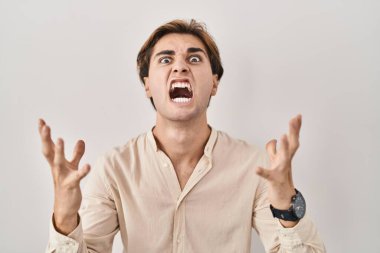 İzole edilmiş arka planda duran genç adam kızgın ve çılgın bir şekilde bağırıyor ve agresif bir ifade ve kollarla bağırıyor. hüsran kavramı. 