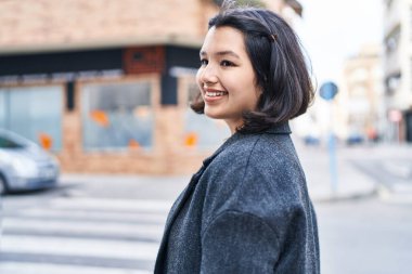 Gülümseyen genç bir kadın sokağın kenarına bakıyor kendinden emin.