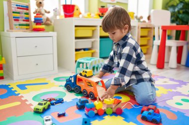 Tatlı İspanyol çocuk arabalarla oynuyor. Anaokulunda yerde oturuyor.