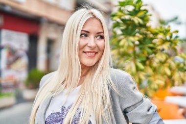 Sokakta kendine güvenen genç sarışın kadın gülümsüyor