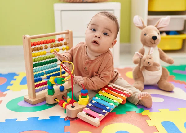 可敬的是 他的惊慌失措的幼儿坐在幼儿园的地板上玩木琴 — 图库照片