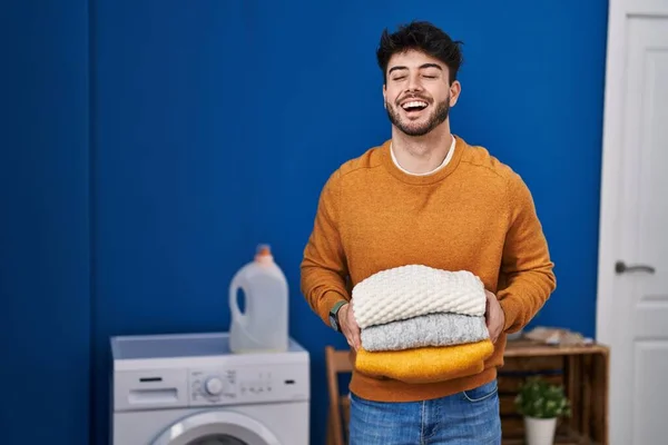 Hispanic Man Beard Holding Clean Folded Laundry Smiling Laughing Hard — Φωτογραφία Αρχείου
