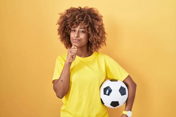 Young Hispanic Woman Curly Hair Holding Football Ball Serious Face — Stockfoto