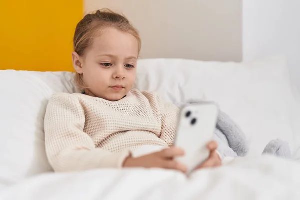Adorable Blonde Girl Using Smartphone Sitting Bed Bedroom — Stok fotoğraf