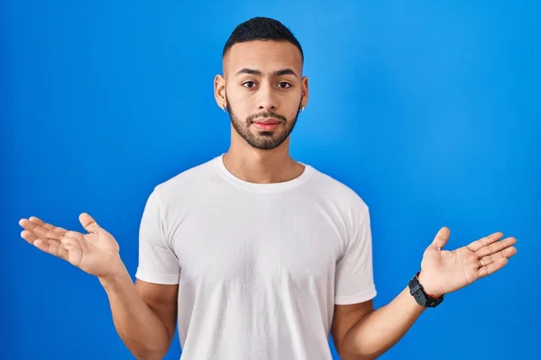 Young Hispanic Man Standing Blue Background Clueless Confused Expression Arms — ストック写真