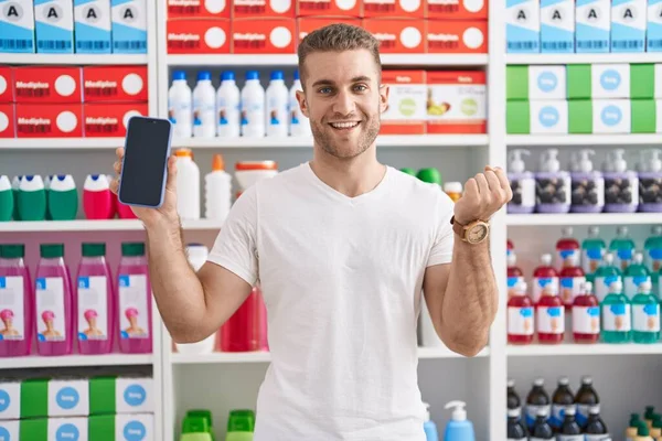 Young Caucasian Man Working Pharmacy Drugstore Showing Smartphone Screen Screaming — Stockfoto