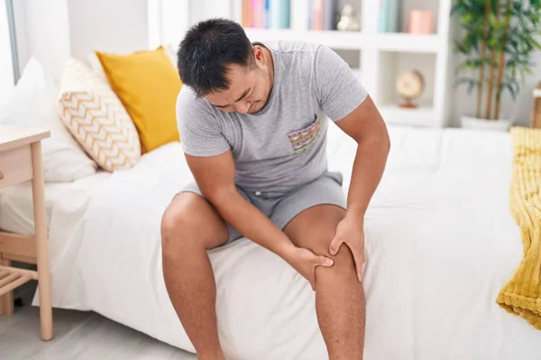 Young Chinese Man Suffering Knee Injury Sitting Bed Bedroom — Foto de Stock