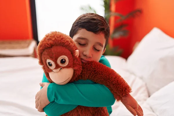 愛らしいHispanic男の子巨大猿人形座っています上のベッドルームで — ストック写真
