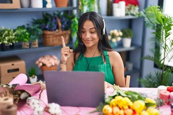 Brunette woman working at florist shop doing video call smiling with an idea or question pointing finger with happy face, number one