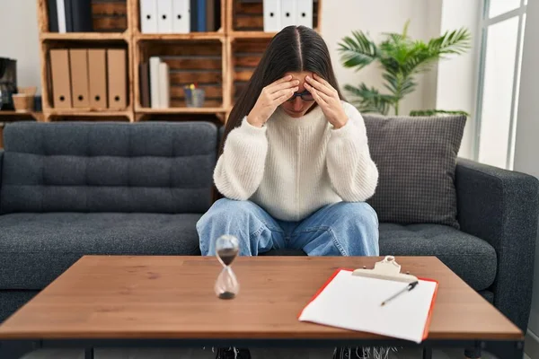 Young hispanic woman patient depressed having psychology session at clinic