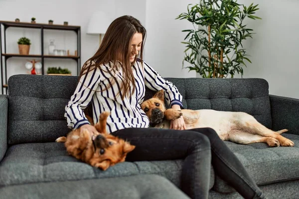 Young hispanic woman smiling confident sitting on sofa with dogs at home
