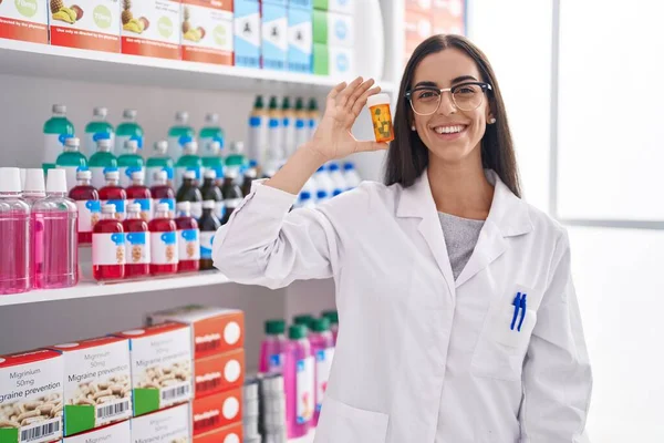 Young Beautiful Hispanic Woman Pharmacist Smiling Confident Holding Pills Bottle — ストック写真