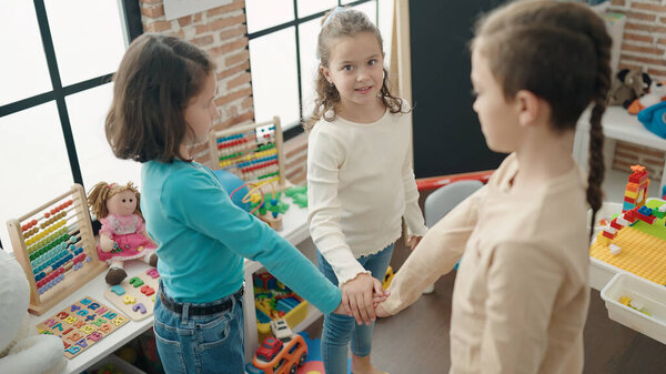 Группа детей, уверенно улыбающихся, стоя в детском саду с поднятыми руками