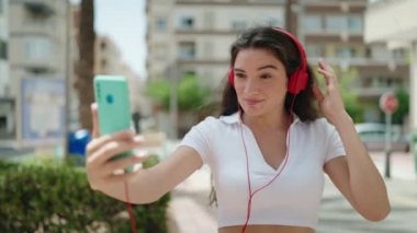Young hispanic woman smiling confident having video call at street