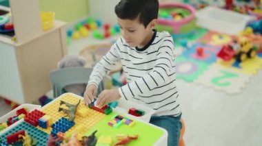 Anaokulundaki masada oturan, inşaat bloklarıyla oynayan sevimli İspanyol çocuk.
