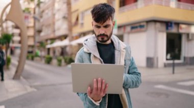 Sokakta dizüstü bilgisayar kullanmaktan endişelenen genç bir İspanyol.