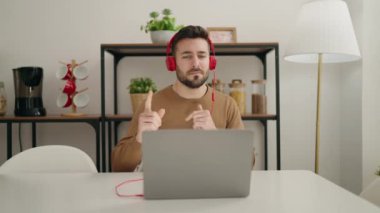 Genç İspanyol adam evde oturmuş müzik dinliyor ve dans ediyor.