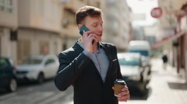 Kafkasyalı genç adam akıllı telefonda konuşuyor. Sokakta kahve içiyor.