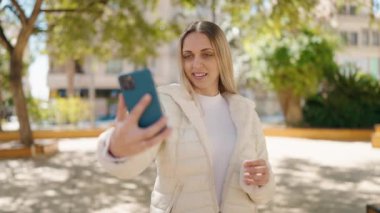 Young woman smiling confident making selfie by the smartphone at park