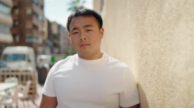 Young chinese man smiling confident standing at street