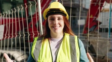 Young beautiful plus size woman architect doing ok gesture with thumbs up speaking at street