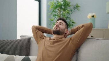 Genç İspanyol adam, ellerini başının üstüne koyup evinde kanepede oturarak rahatladı.