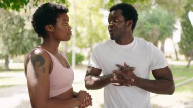 African american man and woman couple stretching arms at park