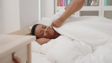 Afro-Amerikalı kadın yatakta uzanıyor. Yatak odasında uyuyor.