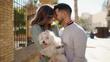 Young couple kissing and hugging dog at street